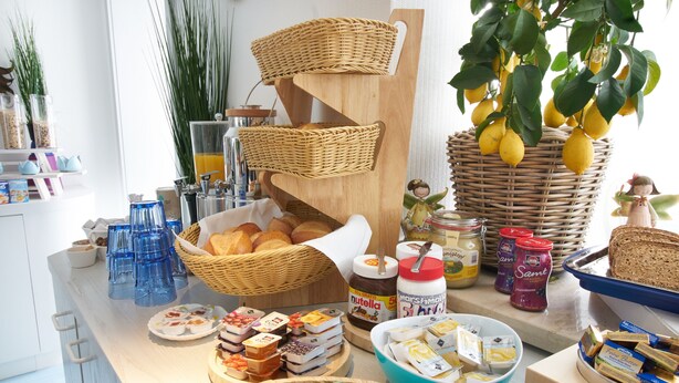 A breakfast buffet with various food items, baskets, and jars of spreads. - Hotel Zum Eisenhammer (Oberhausen)