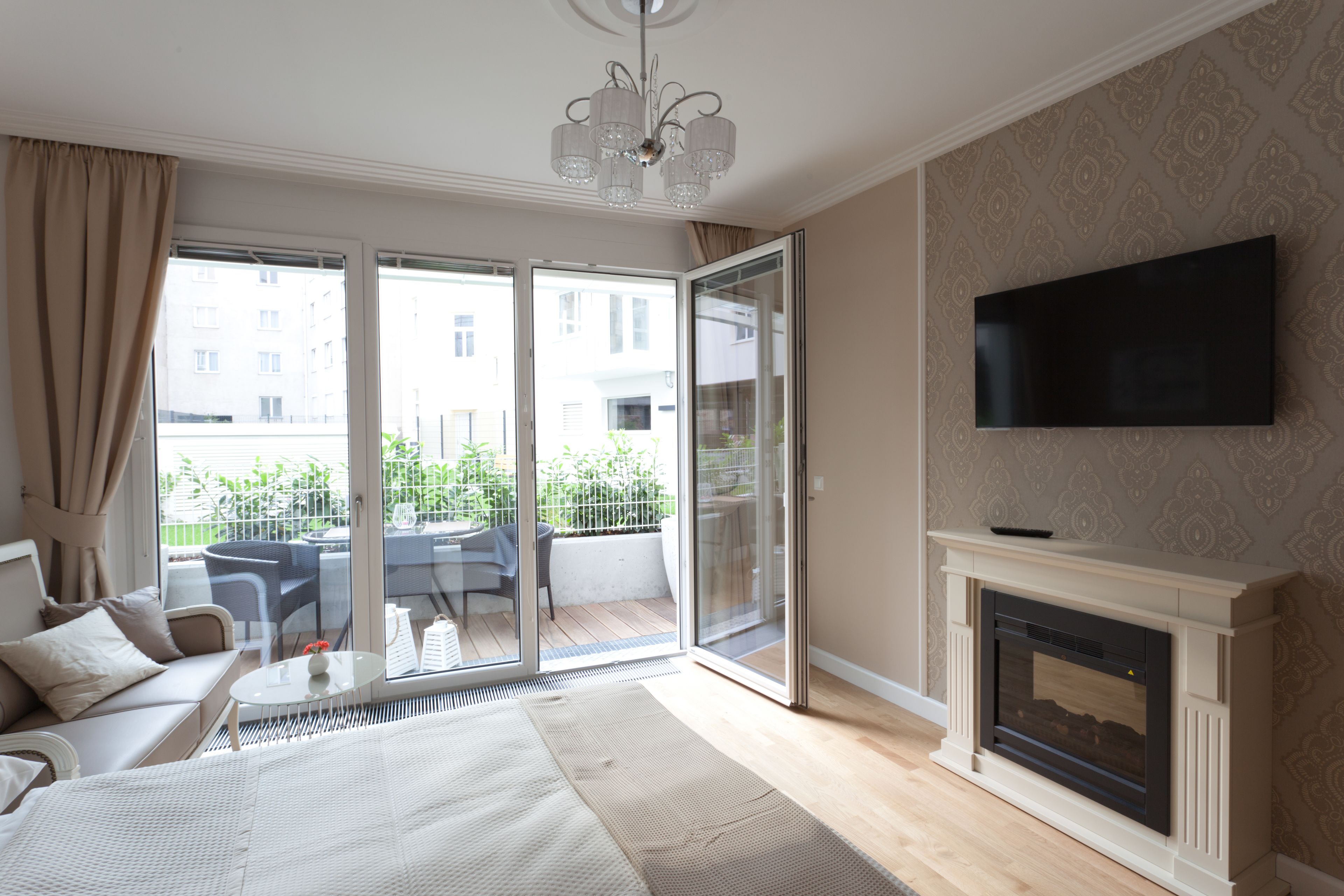 Un dormitorio moderno con una cama grande, chimenea, televisor y puerta corrediza de vidrio que da a un balcón.