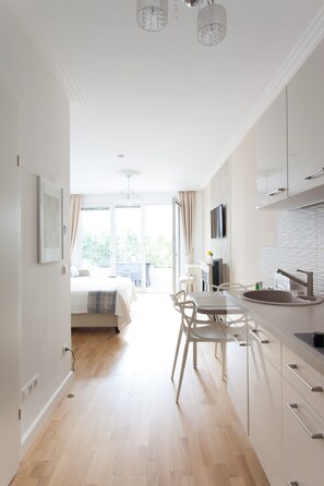 A modern kitchen with white cabinets, a sink, and a dining area with chairs.