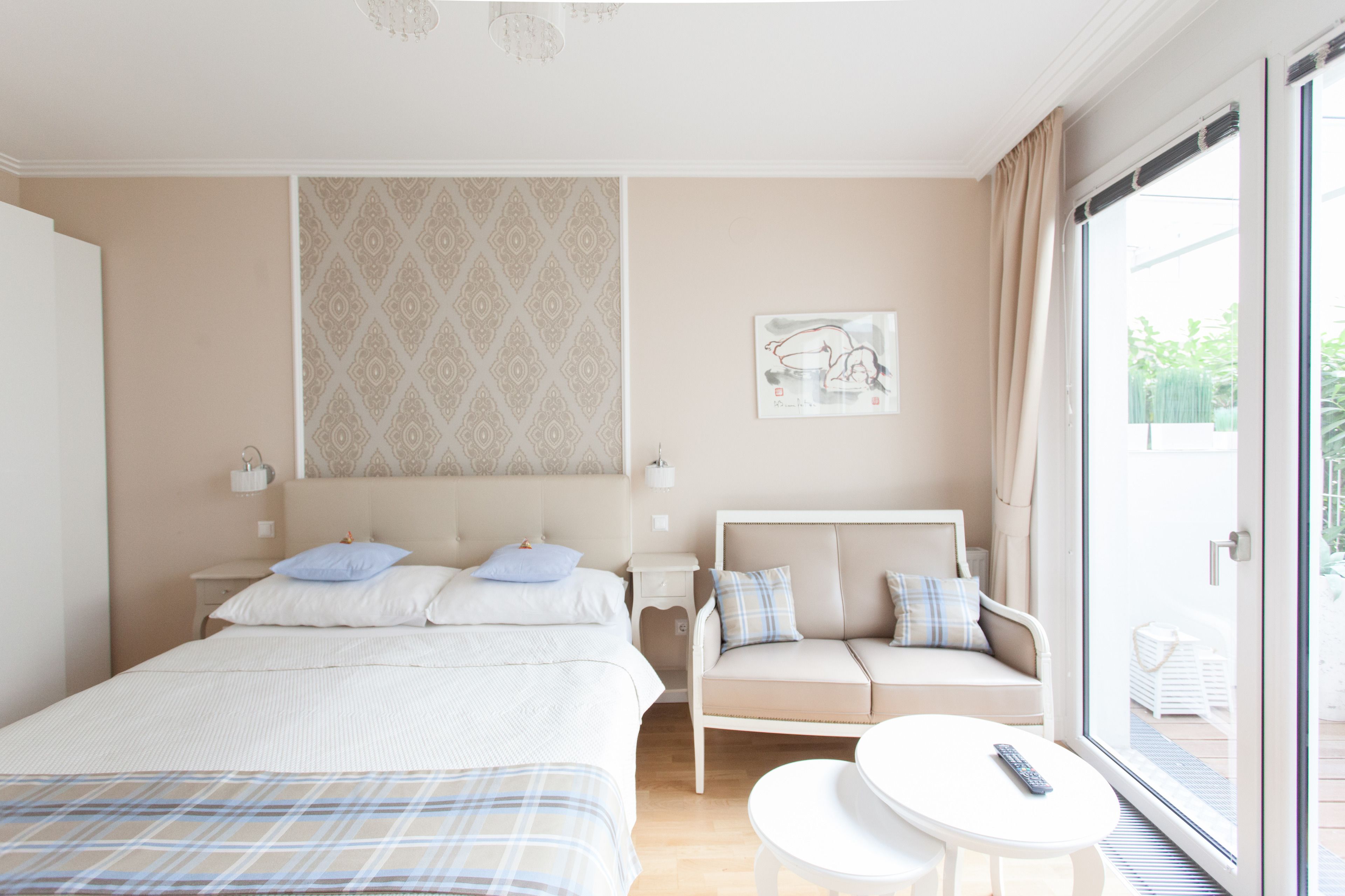 A hotel room with a bed, a sofa, a small table, and a window with curtains.