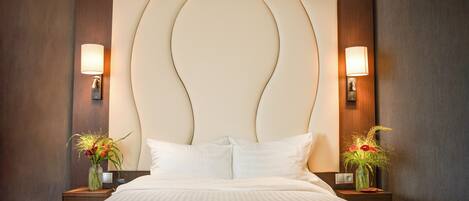 A hotel room with a large bed, two bedside tables with lamps, and decorative vases.