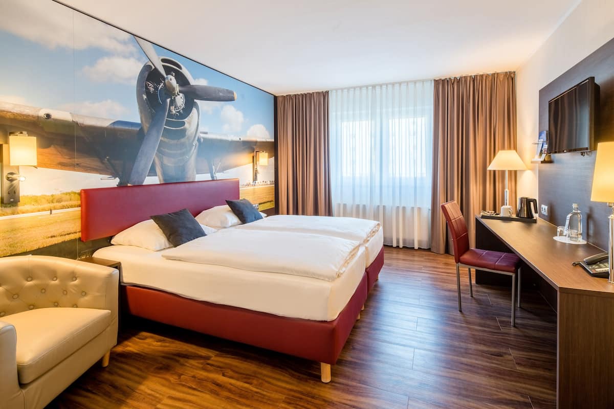 Une chambre d’hôtel avec un grand lit, un bureau, une chaise et un téléviseur.