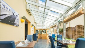 Ein Restaurant mit Glasdecke, blauen Stühlen und gedeckten Tischen.