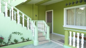 Una escalera con balaustres blancos que conduce a un rellano, una puerta y una ventana con cortina.