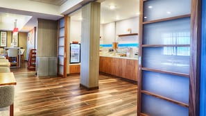 Un restaurante moderno con suelo de madera, una barra con menú y un refrigerador.