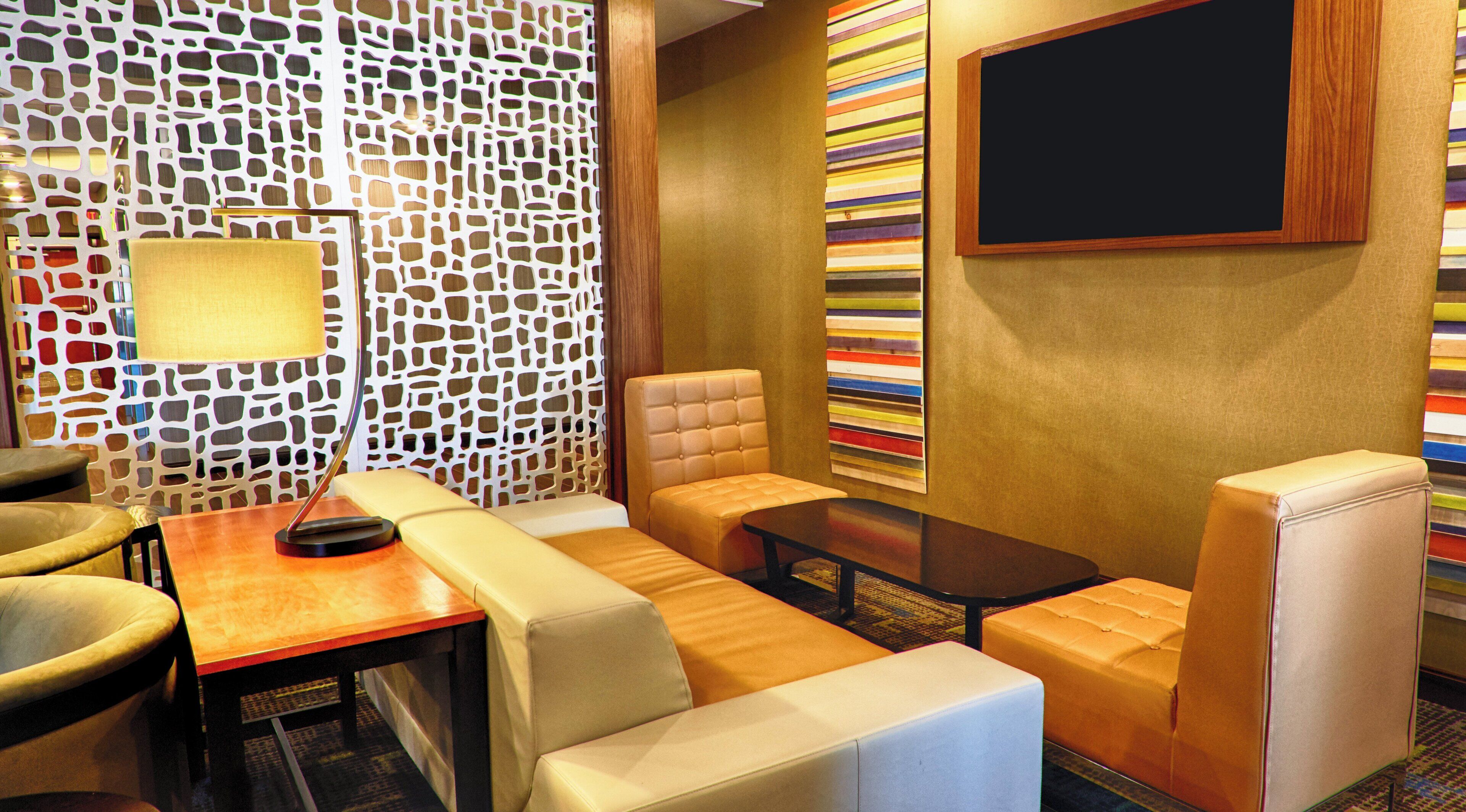 A modern lounge area with a sofa, armchairs, a coffee table, and a wall-mounted TV.