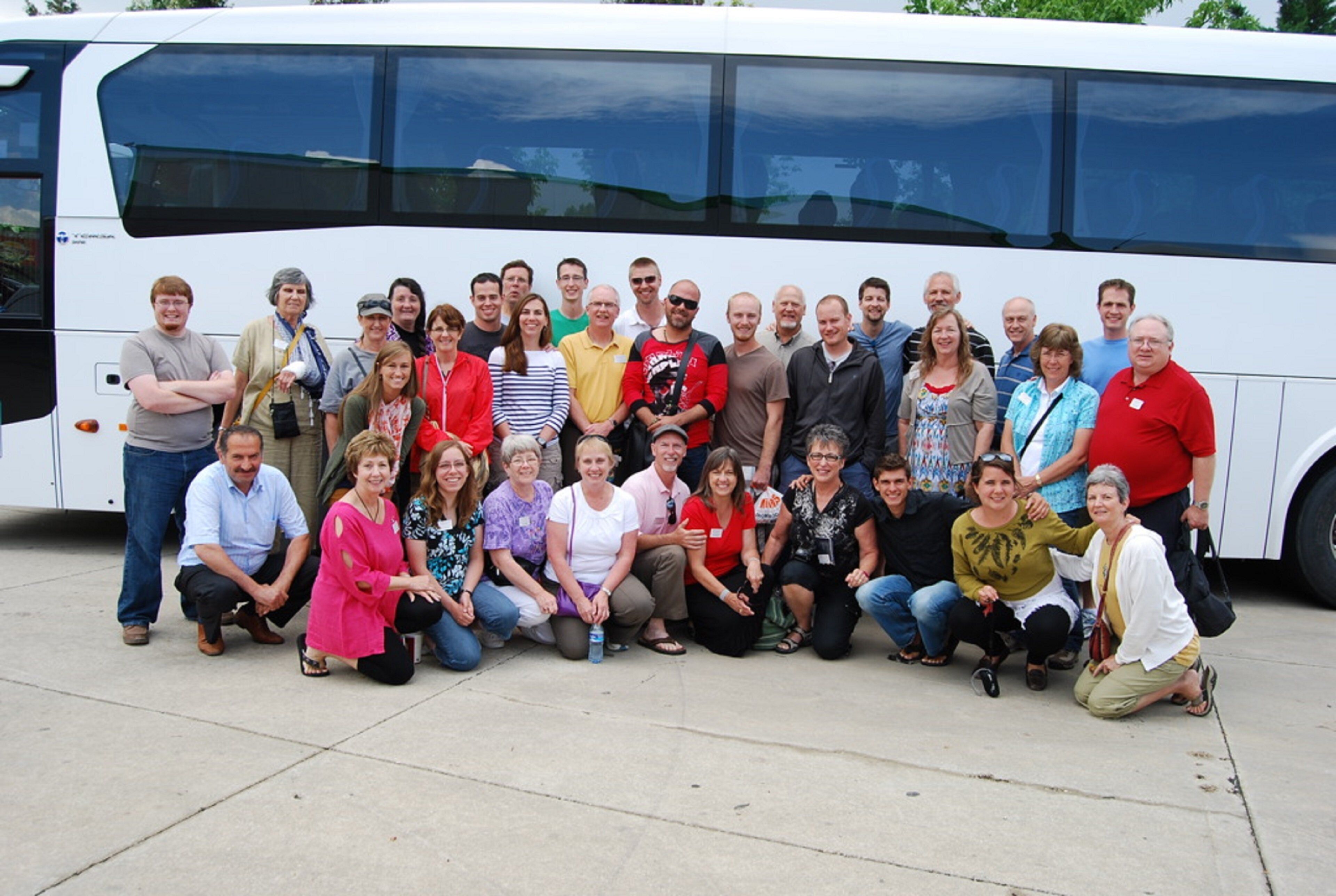 A group of people posing in front of a bus.