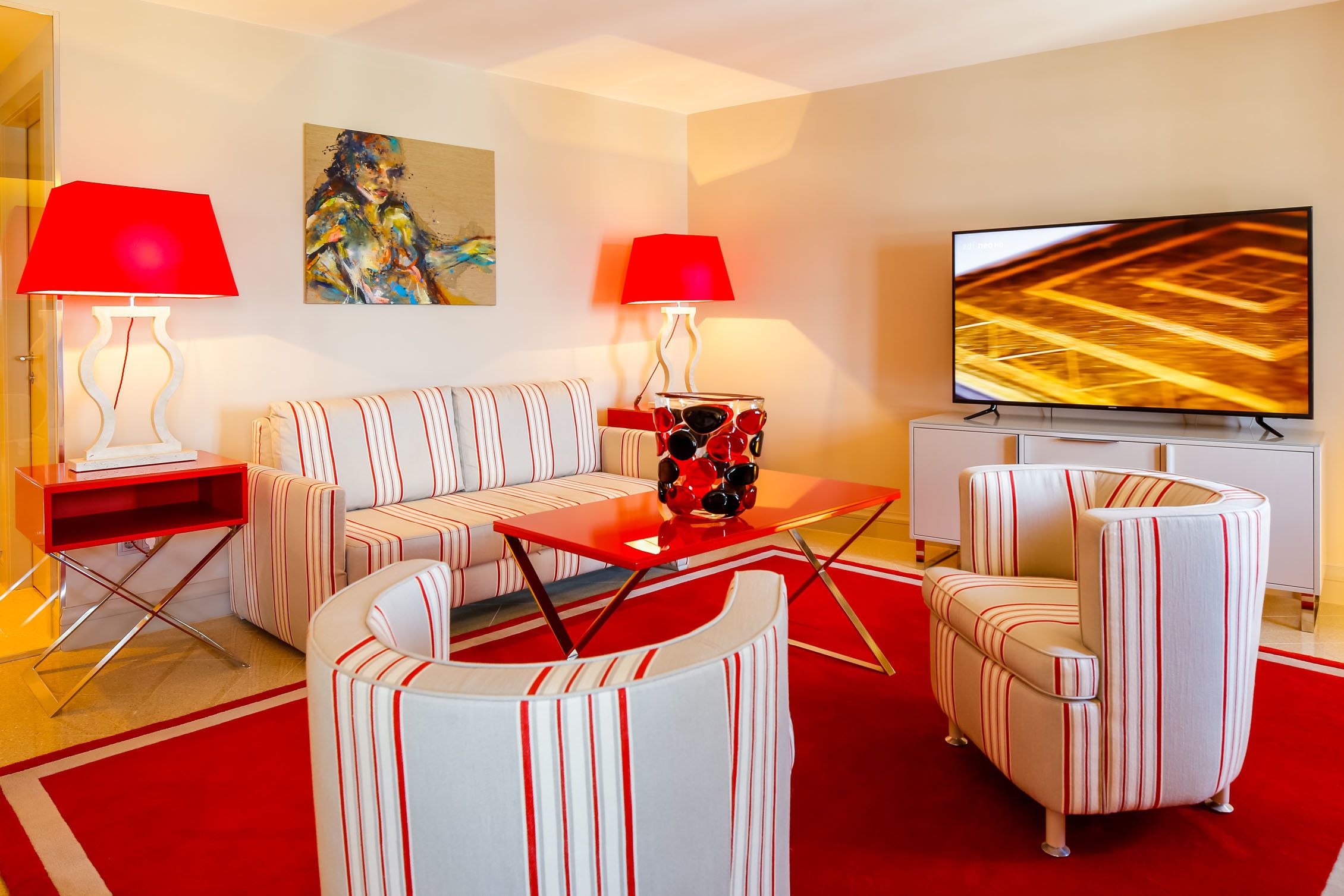 A modern living room with a sofa, armchairs, a coffee table, and a flat-screen TV.