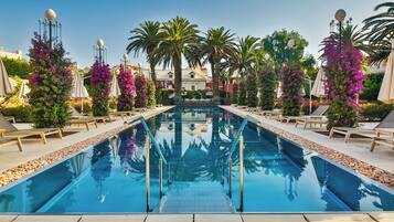 A swimming pool with a clear view of the water, surrounded by lounge chairs and palm trees.