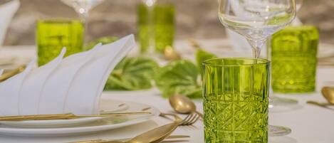Une table dressée avec de la verrerie verte, des couverts dorés et des serviettes blanches.