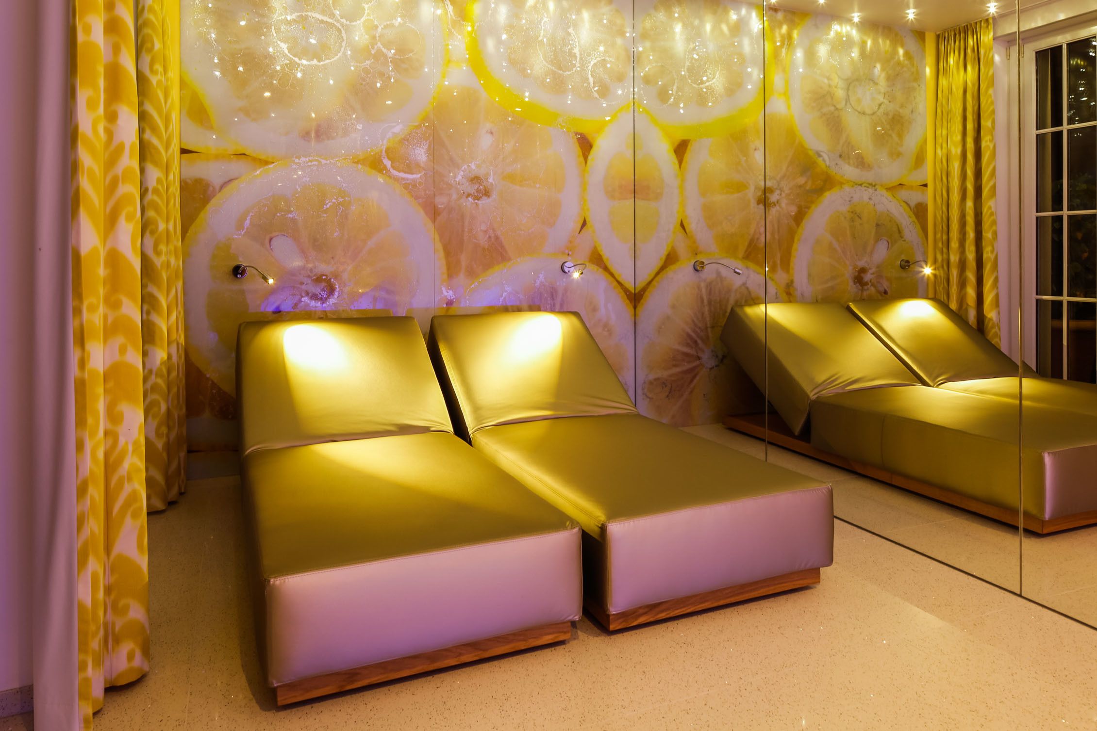 A room with two beds, a mirrored wall, and a patterned curtain.
