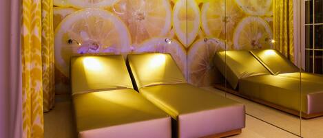 A room with two beds, a mirrored wall, and a patterned curtain.