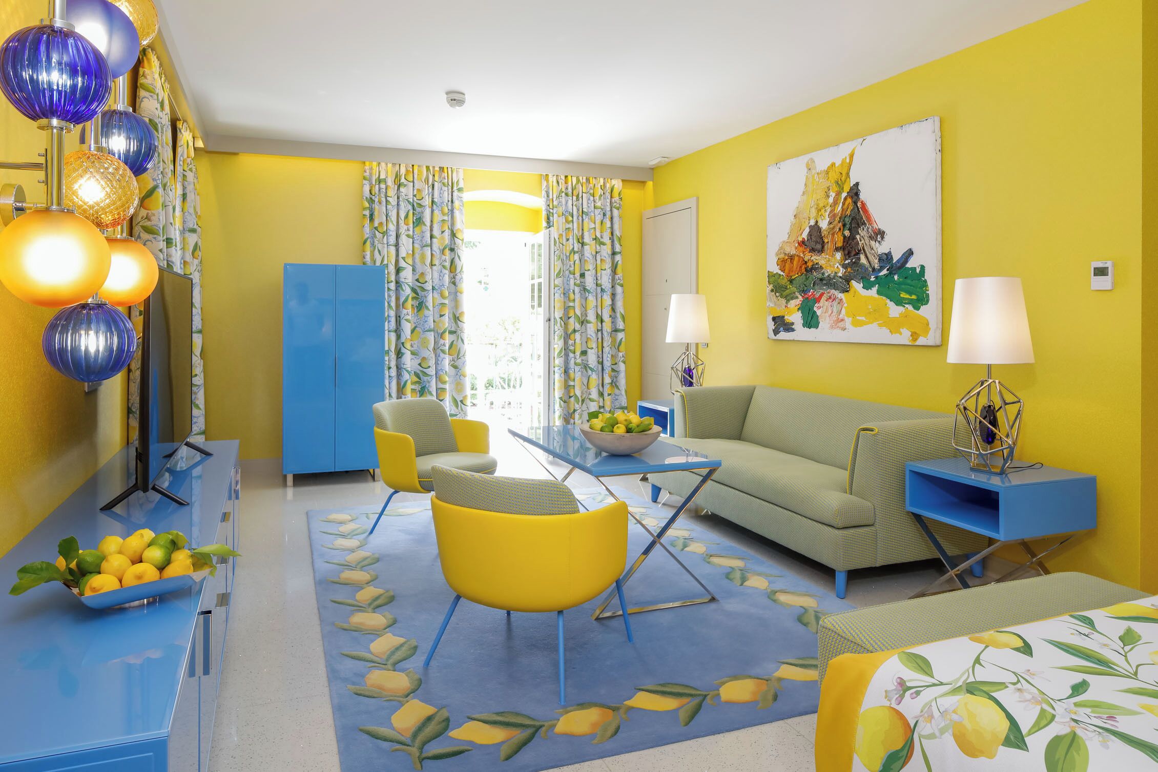 A brightly colored living room with a sofa, chairs, a coffee table, and a TV.