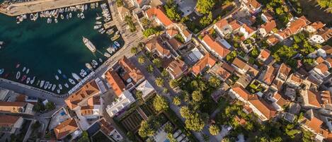 An aerial view of a coastal town with a marina, traditional buildings, and a central square.