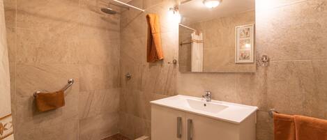 Un baño moderno con ducha, inodoro, lavabo y espejo.