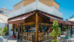 Ein Restaurant mit Außenbereich, einer Holzbar und einem weißen Balkon.