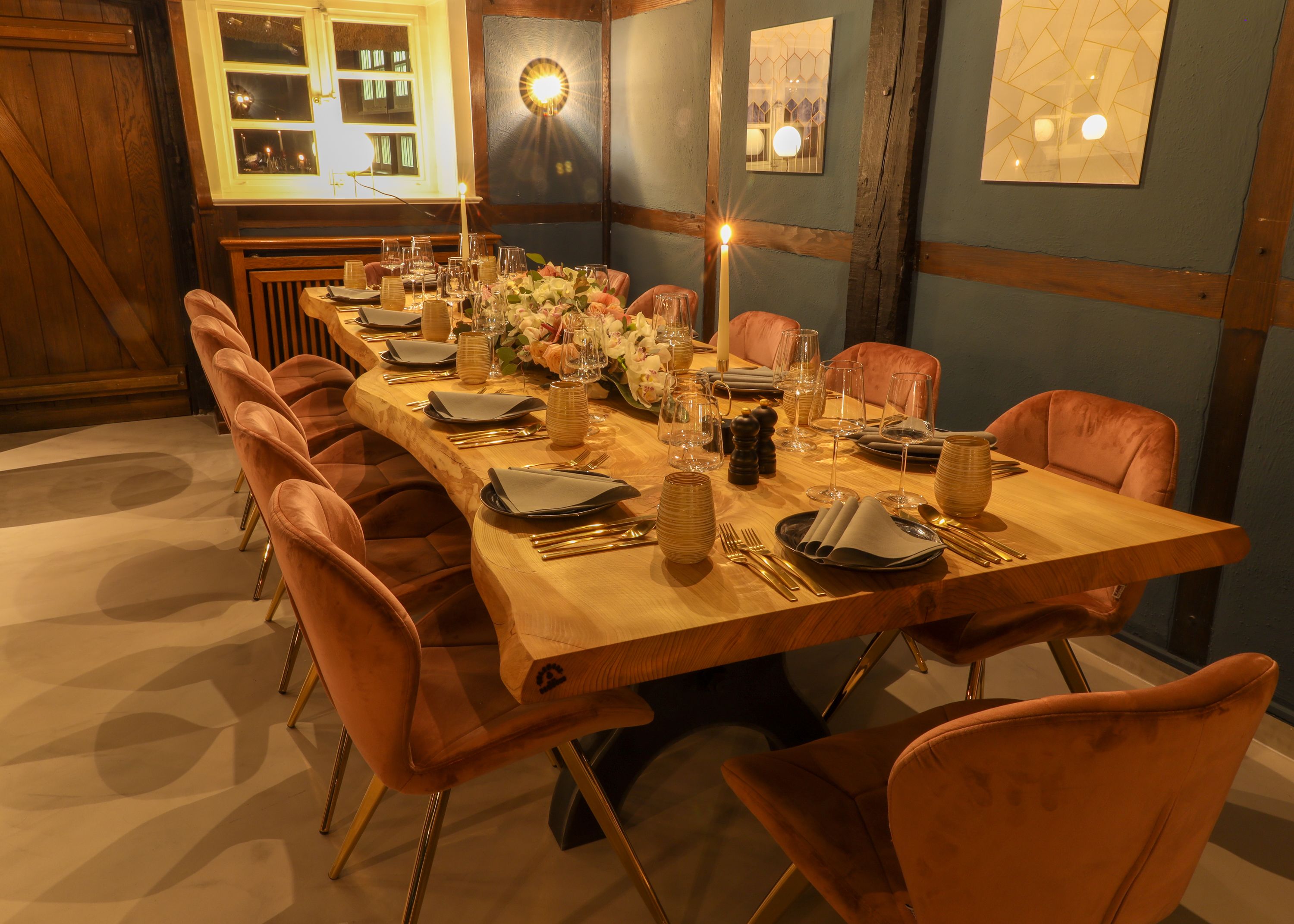 A long dining table set with chairs, candles, and a floral centerpiece.