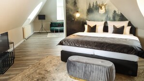 Une chambre moderne avec un grand lit, une télévision et une fresque murale sur le thème de la forêt.