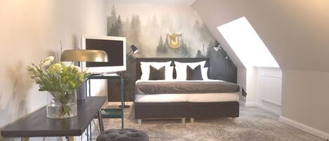 Un dormitorio con cama, escritorio, televisor y un mural en la pared.