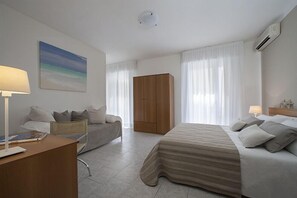 A modern hotel room with a bed, a sofa, a desk, and a wardrobe. - Hotel Galassia (Jesolo)