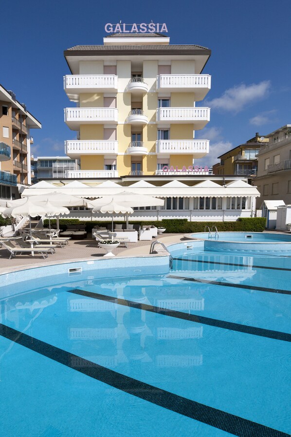 A hotel named GALASSIA with a swimming pool, white umbrellas, and lounge chairs. - Hotel Galassia (Jesolo)