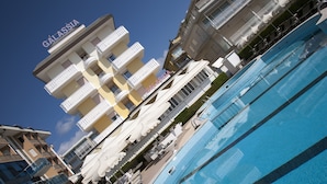 A hotel with a pool, multiple balconies, and outdoor seating areas. - Hotel Galassia (Jesolo)