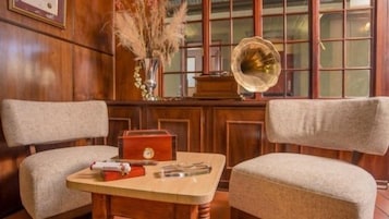 Una habitación con dos sillones, una mesita de madera, una caja roja y un tocadiscos.