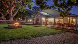 A cozy outdoor seating area with a fire pit, surrounded by a well-maintained lawn and a stone wall. - Saragossa Game Reserve (Emgwenya)