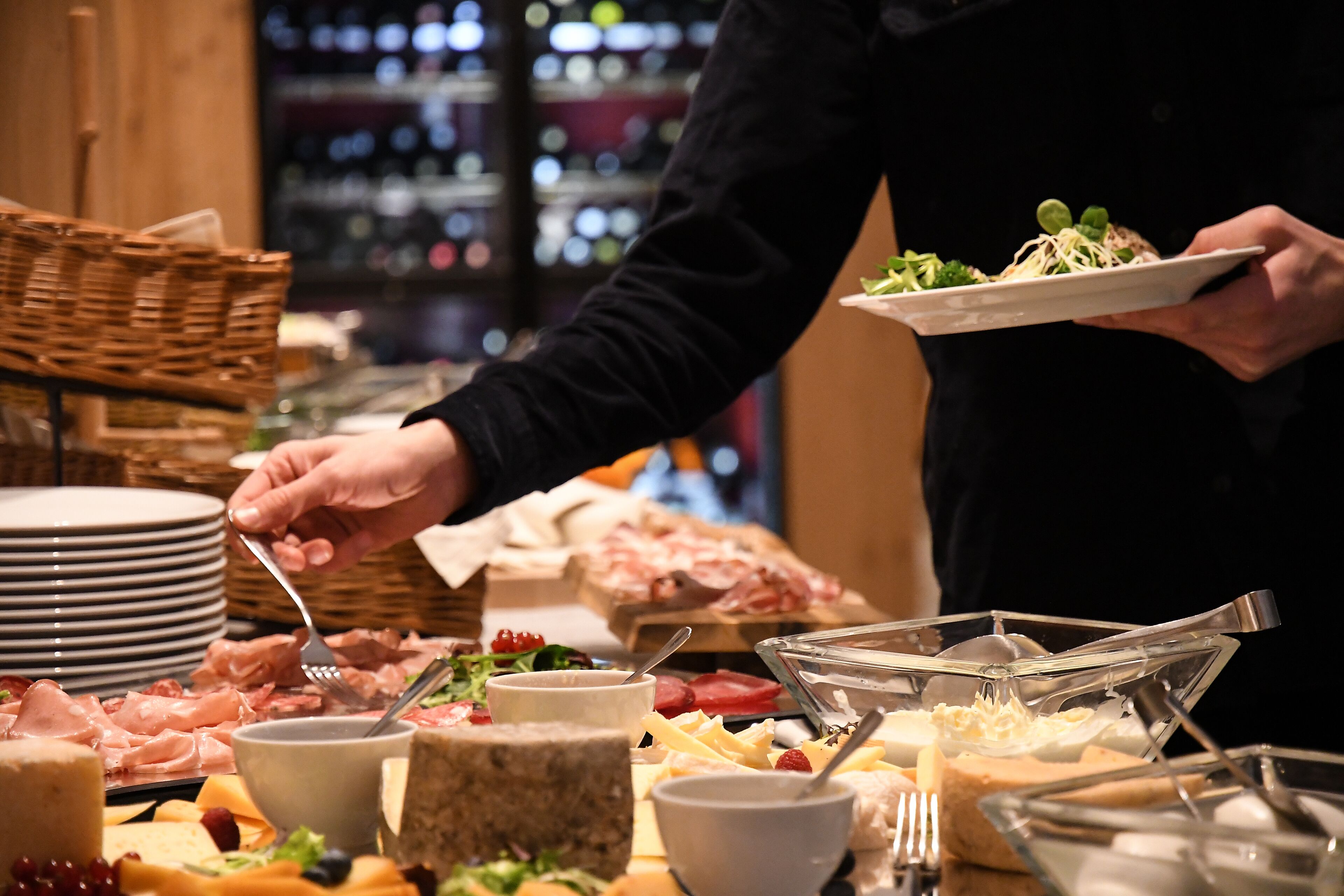 A buffet with various food items and a person serving themselves.