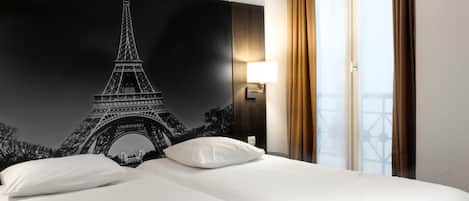 Ein Hotelzimmer mit einem Bett, einer Nachttischlampe und einem großen Wandbild des Eiffelturms.