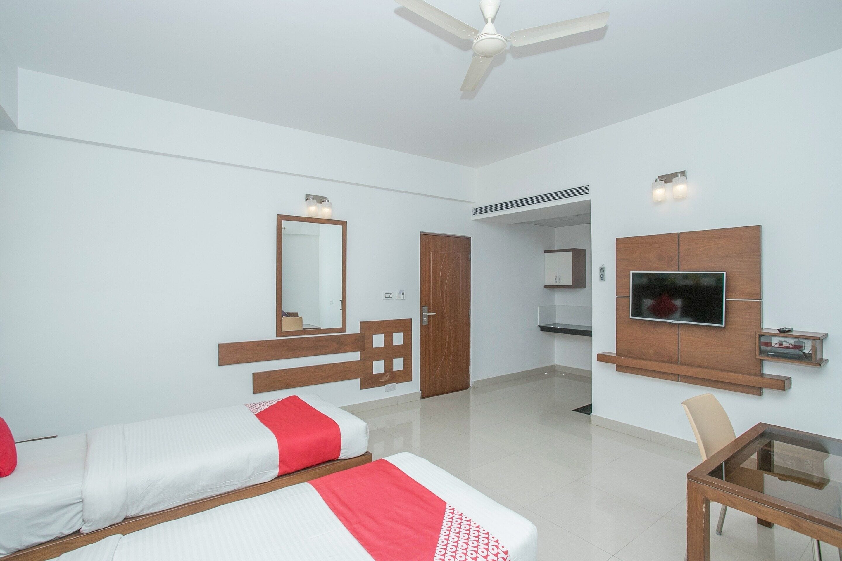 A modern hotel room with a bed, a TV, a ceiling fan, and a small table.