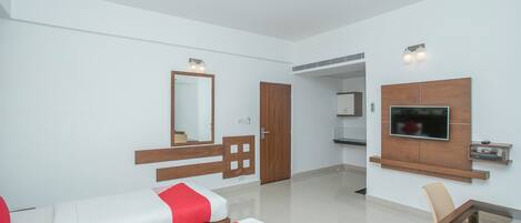 A modern hotel room with a bed, a TV, a ceiling fan, and a small table.