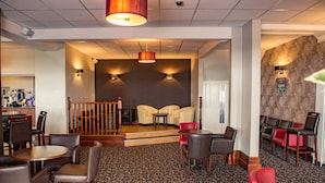 A hotel lobby with a staircase leading to a second floor, a seating area with chairs and tables, and a patterned carpet. - Lothersdale Hotel Morecambe by Belvilla (Morecambe)