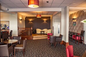 A hotel lobby with a staircase leading to a second floor, a seating area with chairs and tables, and a patterned carpet. - Lothersdale Hotel Morecambe by Belvilla (Morecambe)