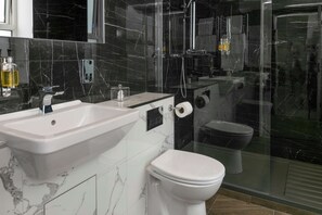 Un baño moderno con lavamanos, inodoro y cabina de ducha de vidrio.