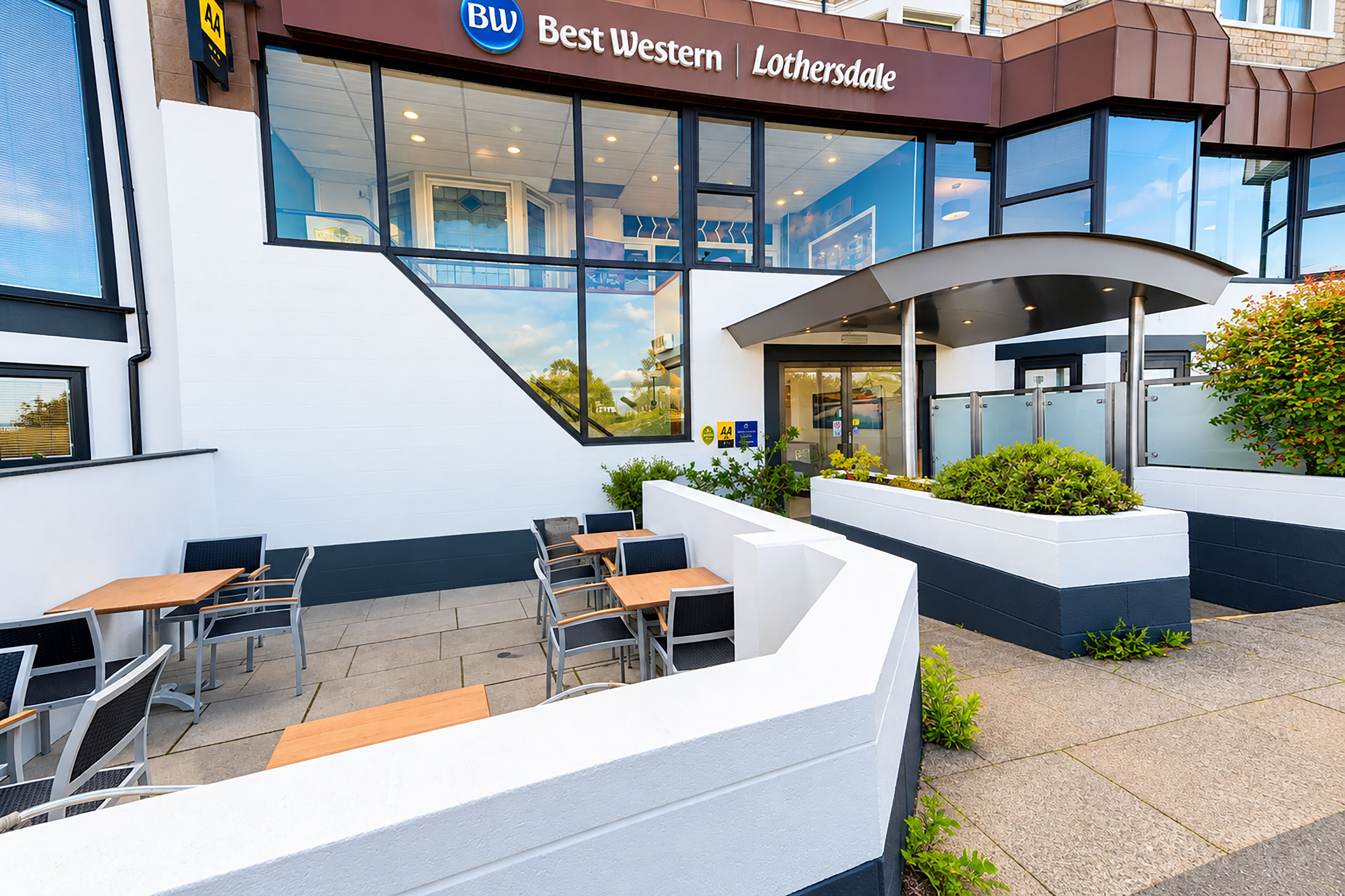 Exterior de un hotel Best Western Lothesdale con asientos al aire libre y una vista despejada de la entrada.