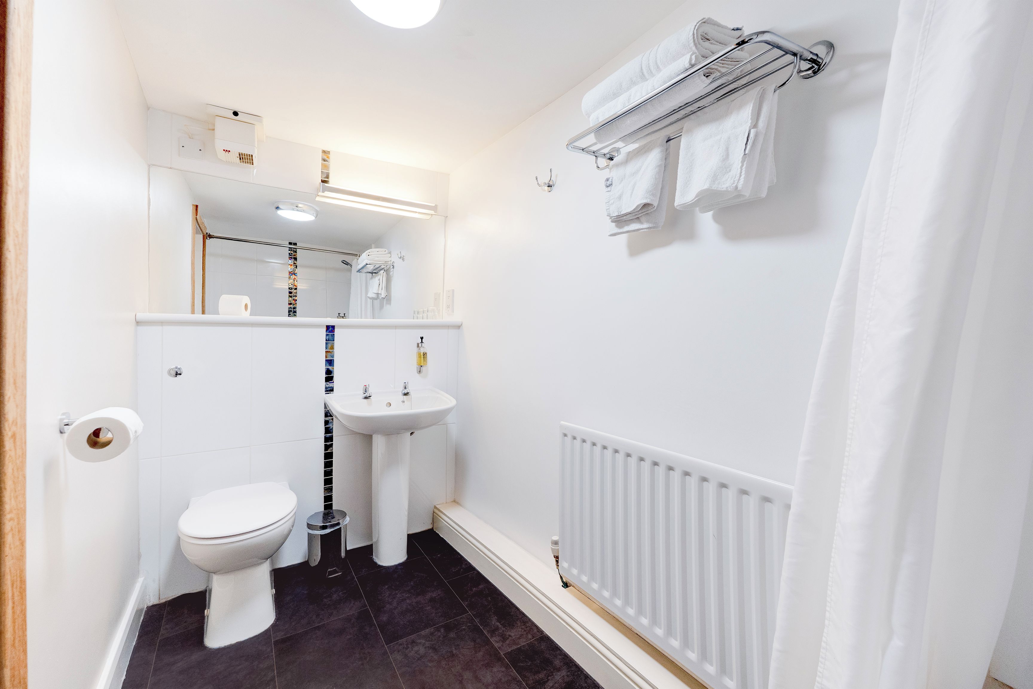 A small, clean bathroom with a toilet, sink, and towel rack.