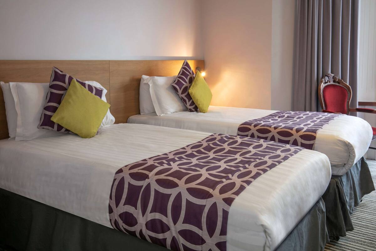 Habitación de hotel con dos camas, cada una con colcha y almohadas estampadas.