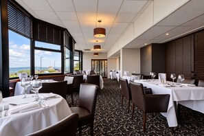 A restaurant with tables set for dining, large windows offering a view, and a patterned carpet. - Lothersdale Hotel Morecambe by Belvilla (Morecambe)