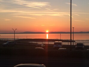 A sunset over a body of water with vehicles parked along the roadside. - Best Western Lancaster Morecambe Lothersdale Hotel (Morecambe)