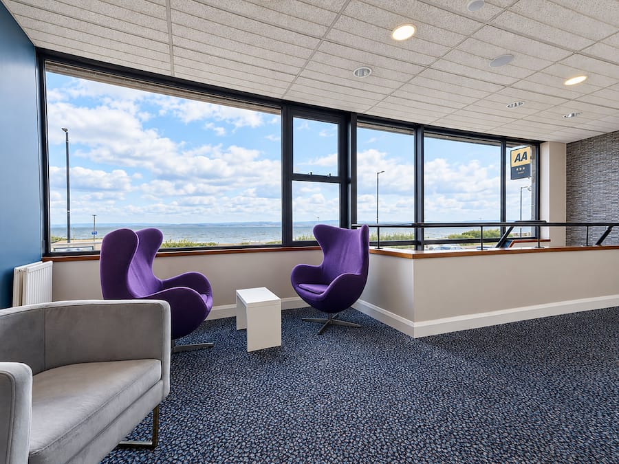 A modern waiting area with large windows, a view of the sea, and a reception desk.