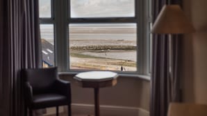 A room with a view of the beach through a large window, a chair, a small table, and a lamp. - Lothersdale Hotel Morecambe by Belvilla (Morecambe)