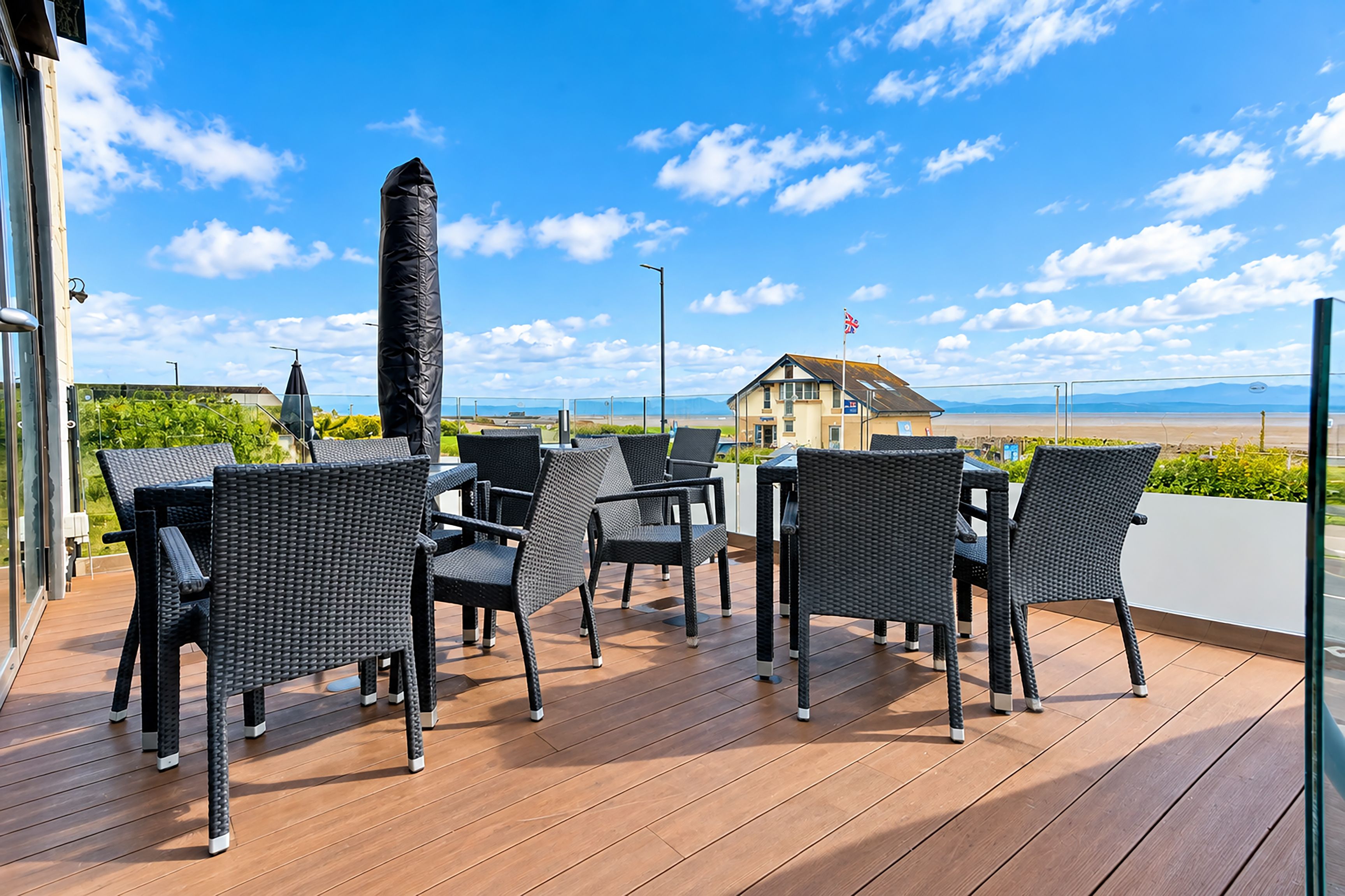 A deck with wicker furniture and a view of the beach.