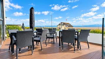 A deck with wicker furniture and a view of the beach.