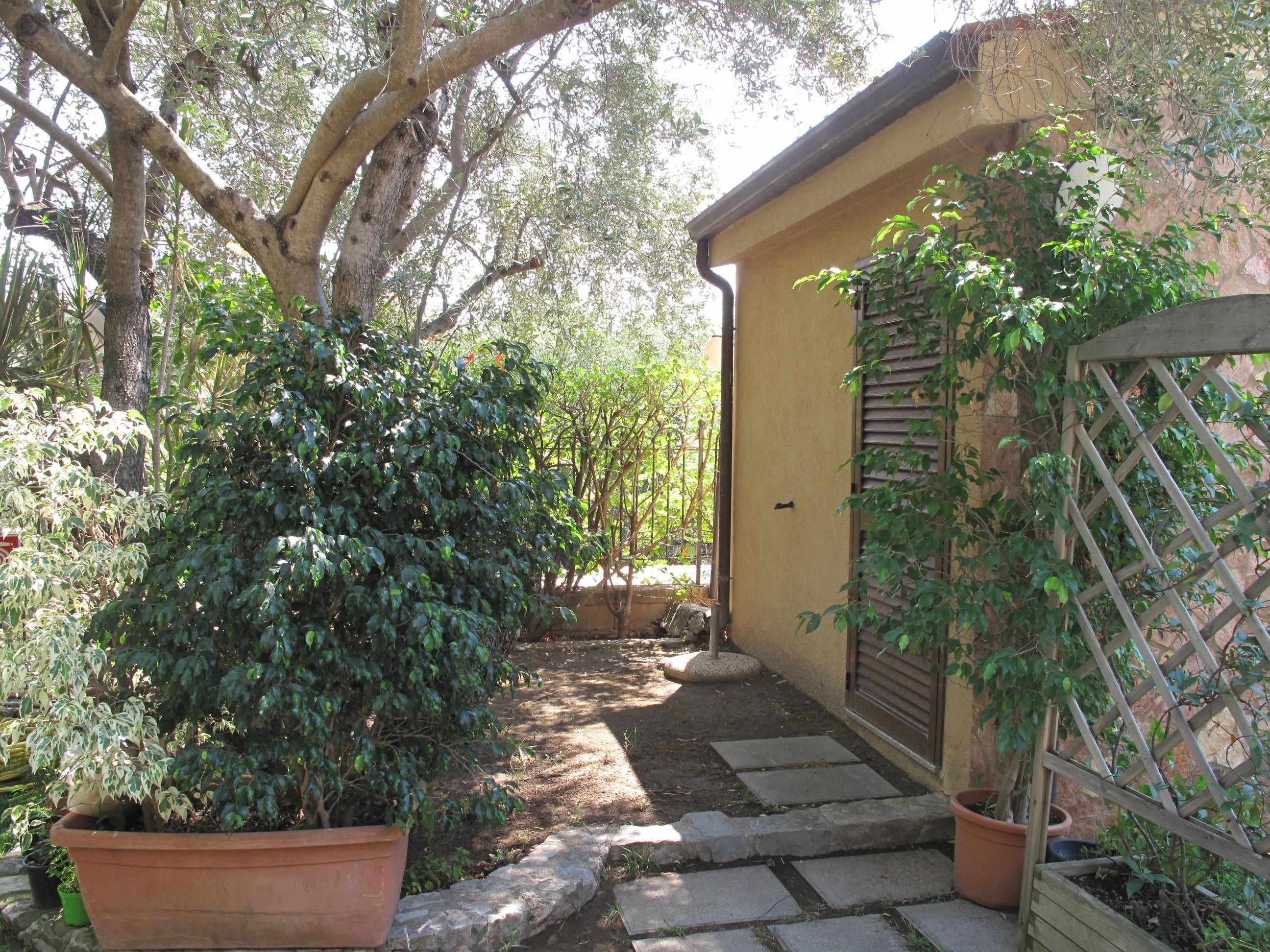 A garden pathway leading to a building with a yellow exterior and a wooden lattice fence.