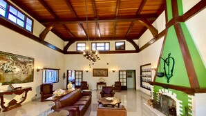 A spacious living room with a high ceiling, a fireplace, and a green accent wall. - Hotel Vila Bavaria (Petrópolis)