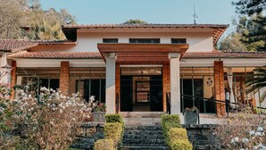 A two-story house with a tiled roof, a covered entrance, and a stone staircase leading to the front door. - Hotel Vila Bavaria (Petrópolis)
