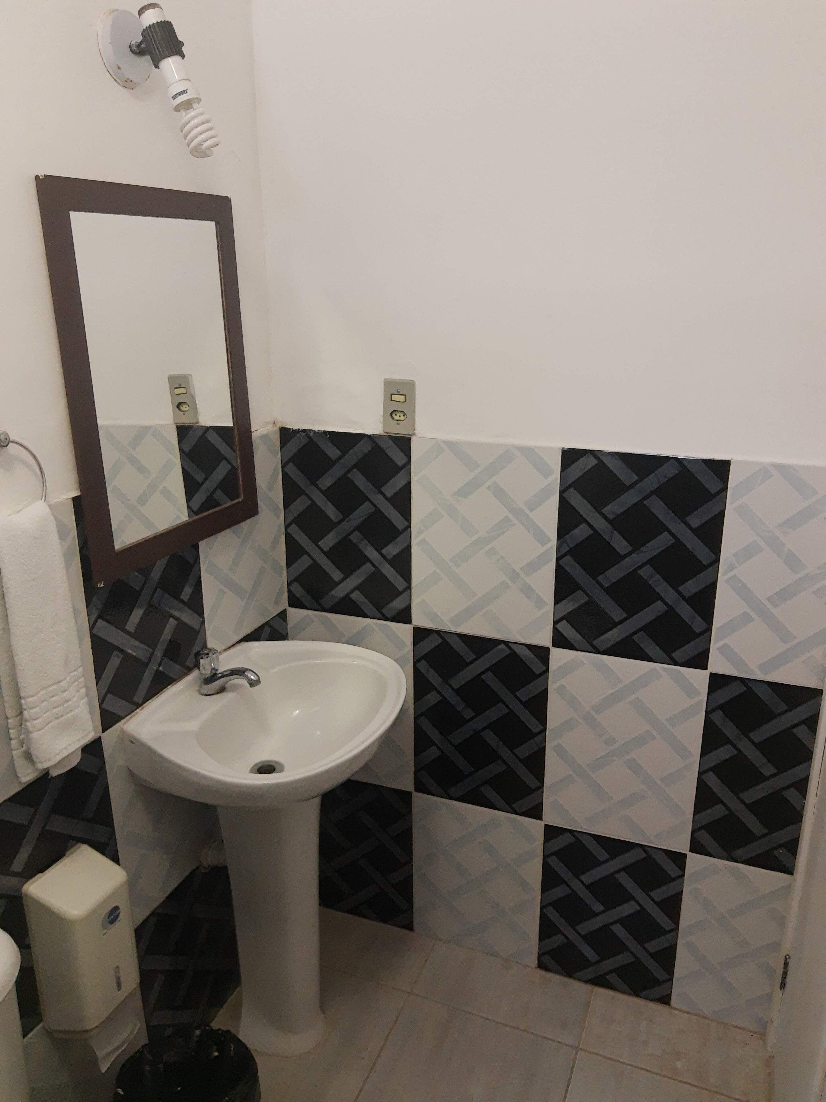 A bathroom with a white sink, a mirror, and patterned tiles.