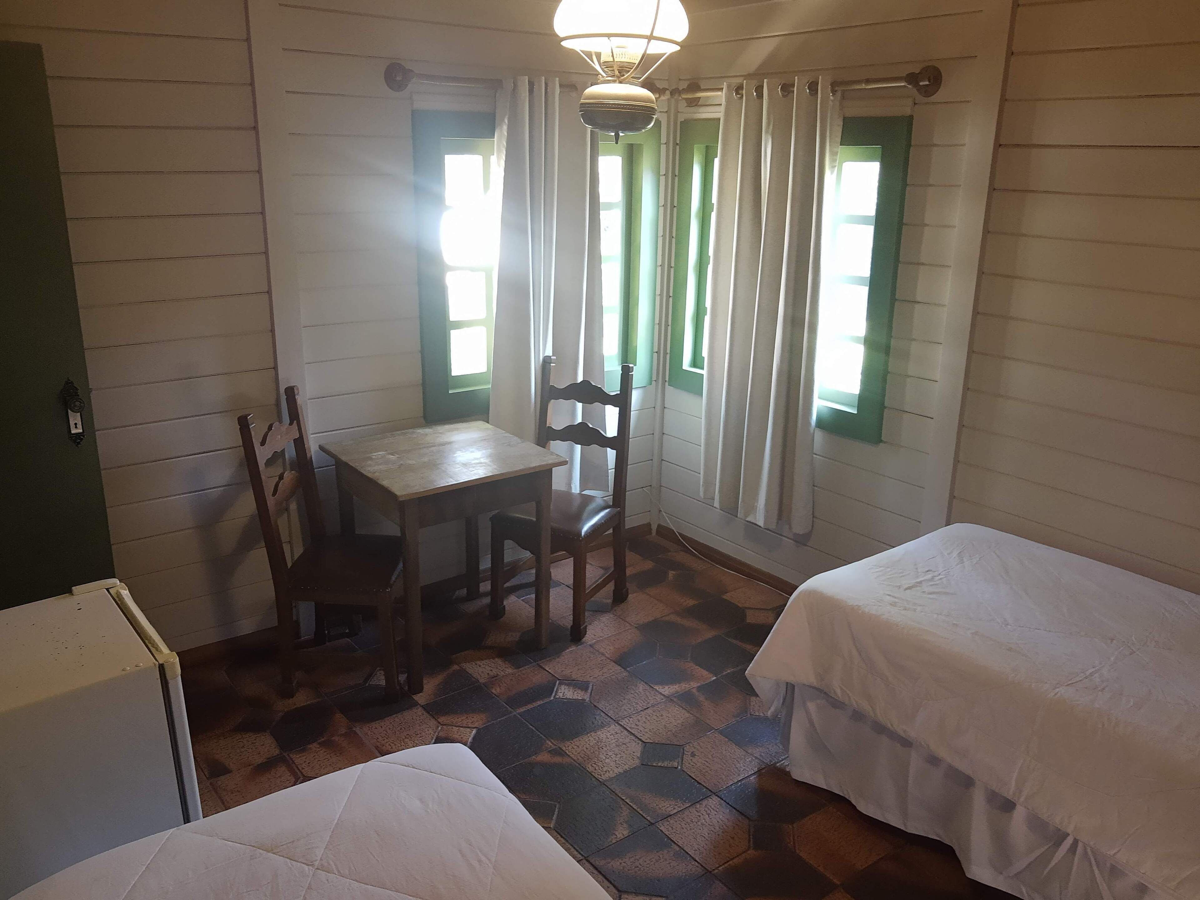 A room with two beds, a table, and a chair.