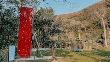Una estructura roja para escalar en un parque con césped y árboles.